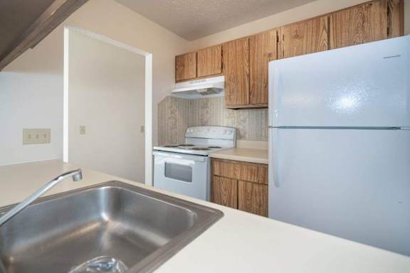 A kitchen with a sink, stove, and refrigerator.