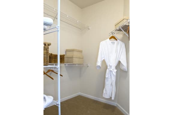 a white robe hangs on a rack in a walk in closet