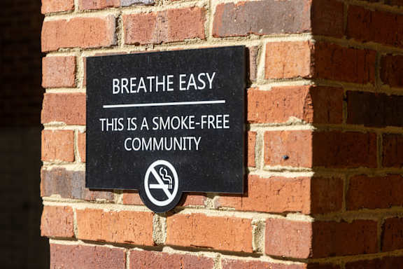 A sign on a brick wall that says "Breathe Easy, this is a smoke-free community.".