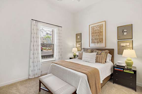 A bedroom with a large bed and a window with curtains.