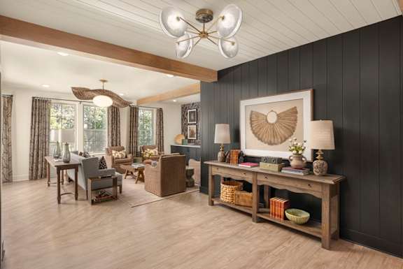 A living room with a wooden floor and a large window with curtains.