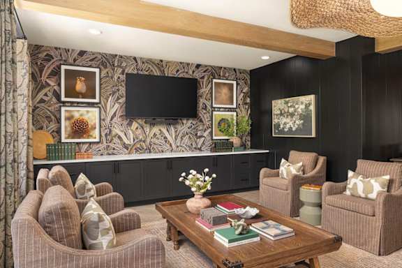 A living room with a brown couch, a coffee table, and a flat screen TV mounted on the wall.