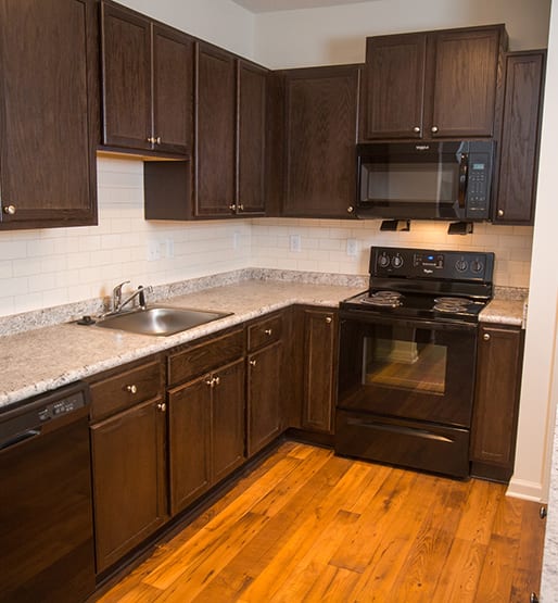 a kitchen with dark wood cabinets and a wooden floor