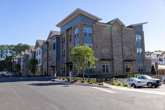A large, modern building with a stone facade and a parking lot in front.