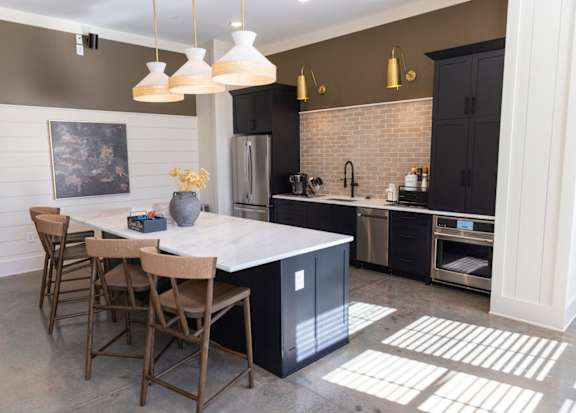 A kitchen with a white island and wooden chairs.