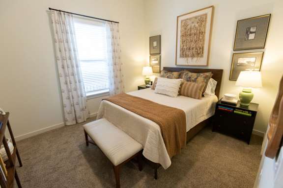 A bedroom with a bed, nightstand, and a window with curtains.
