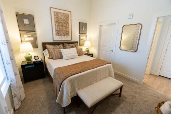 A bedroom with a large bed and a bench in front of it.