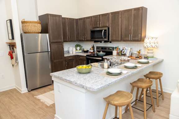A kitchen with a white island and wooden stools.