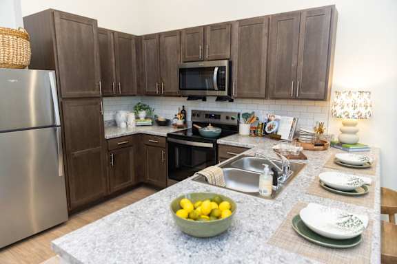 A kitchen with brown cabinets and a stainless steel refrigerator.