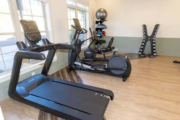 A treadmill and a stationary bike are in a room with a wooden floor.