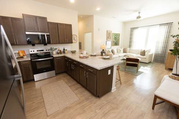 A kitchen with a refrigerator on the left and a dining area with a white couch and chairs.