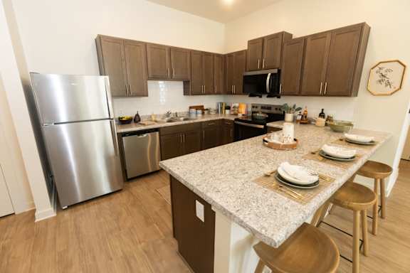 A kitchen with a granite counter top and wooden cabinets.