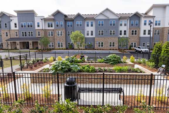 Apartment complex with a black fence and a small garden in front.