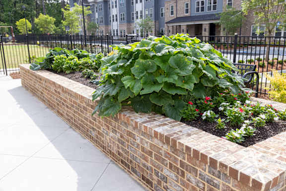 A brick planter with a variety of plants in it.