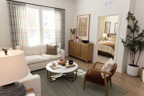 A living room with a white couch, a coffee table, and a chair.