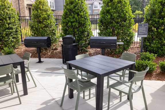 A black table surrounded by green chairs.