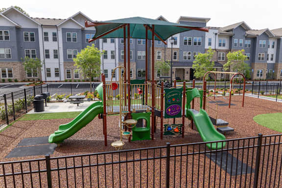 A playground with a green slide and a red and yellow play structure.