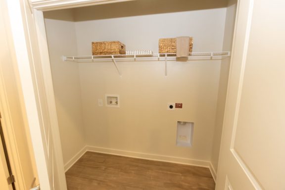 A small, empty closet with two shelves and a door.