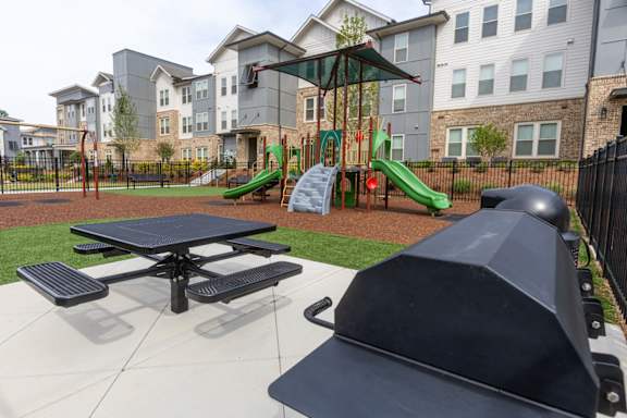 A playground with a slide, swings, and a picnic table.