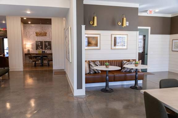 A grey and white hallway with a brown couch and a table with two green drinks on it.