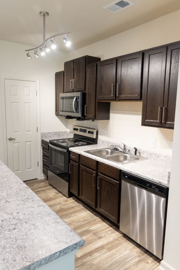 a kitchen with dark wood cabinets and stainless steel appliances