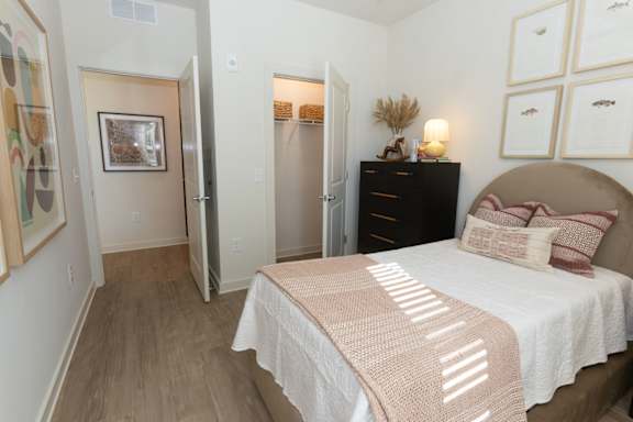 A bedroom with a bed, dresser, and a painting on the wall.