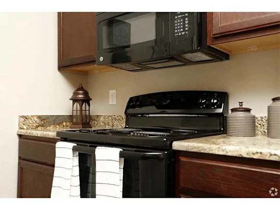 A black microwave oven is mounted above a black stove in a kitchen.