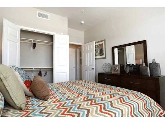 A bedroom with a bed covered in a multicolored blanket.
