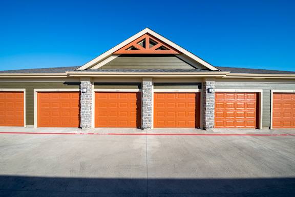 A garage with orange doors and a grey roof.