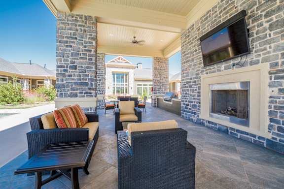 A patio with a stone fireplace and a television mounted on the wall.