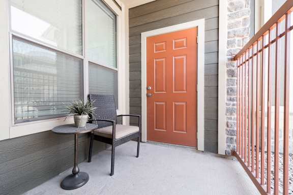 A small table with a plant on it sits on a porch.
