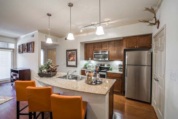 A kitchen with a counter and orange chairs.