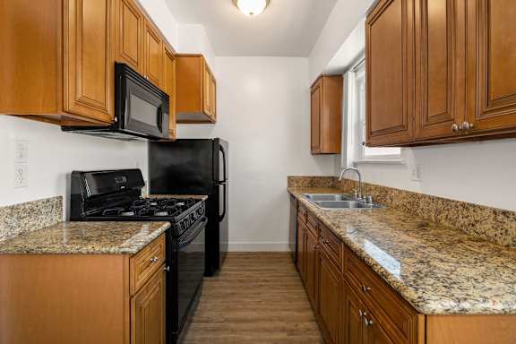 A kitchen with granite countertops and wooden cabinets.