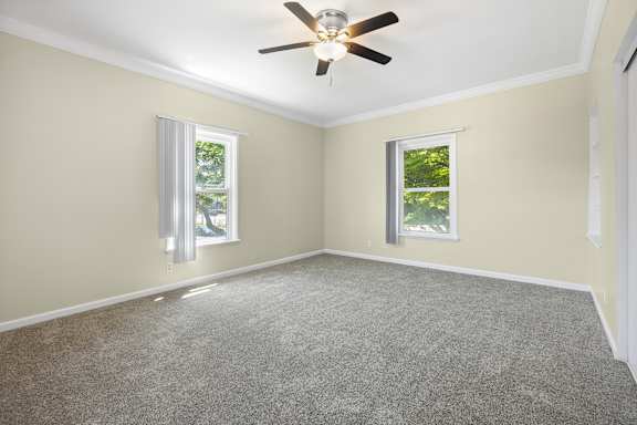 A room with a ceiling fan and two windows.