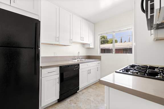 A kitchen with black appliances and white cabinets.