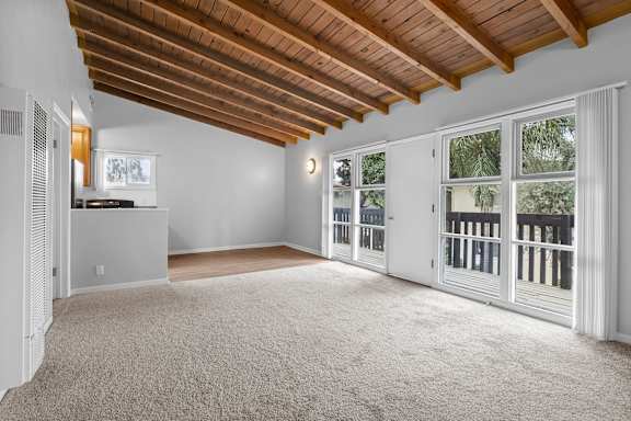 an empty living room with large windows and a balcony