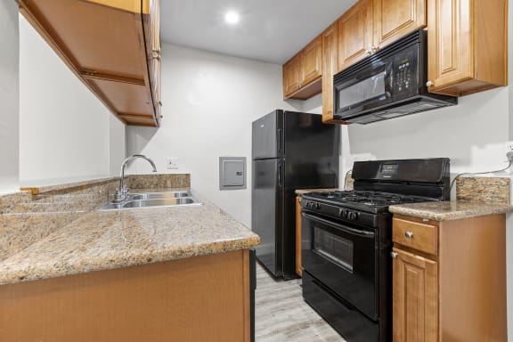 a kitchen with black appliances and granite counter tops at Parkview Terrace Apartments, Sherman Oaks, California