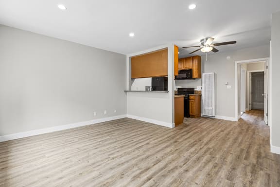 an empty living room with a kitchen and a ceiling fan at Parkview Terrace Apartments, California