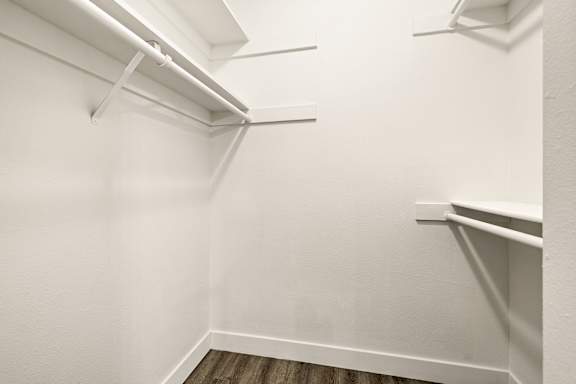 A white closet with a wooden floor and three shelves.