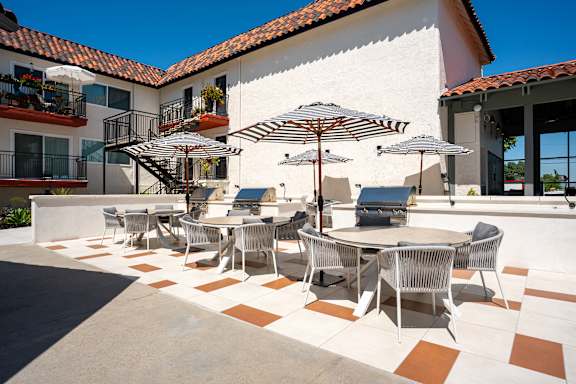 A patio with a table and chairs under umbrellas.