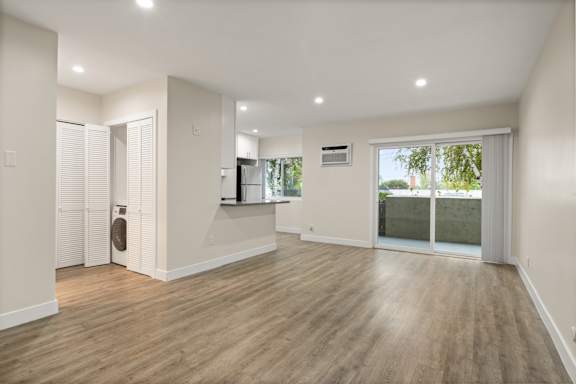A spacious room with wooden flooring and white walls.