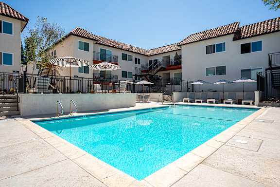 A swimming pool in front of a building with a fence around it.