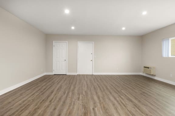 an empty living room with white walls and wood floors