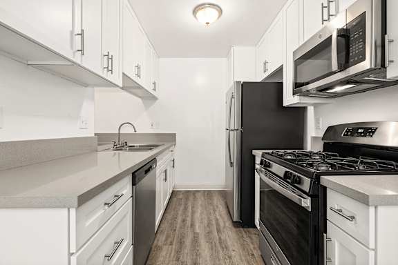A kitchen with white cabinets and black appliances.