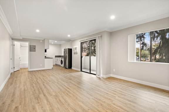 A spacious room with wooden floors and a washer and dryer stacked together.