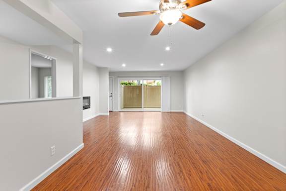 A room with a ceiling fan and wooden flooring.