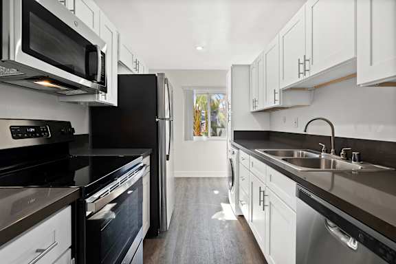 A modern kitchen with black appliances and white cabinets.