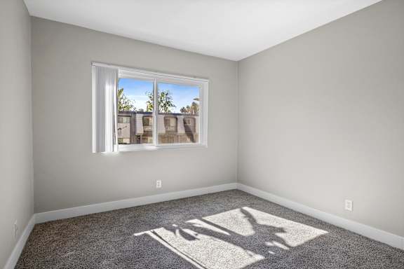 A room with a large window and a shadow of a person on the carpet.