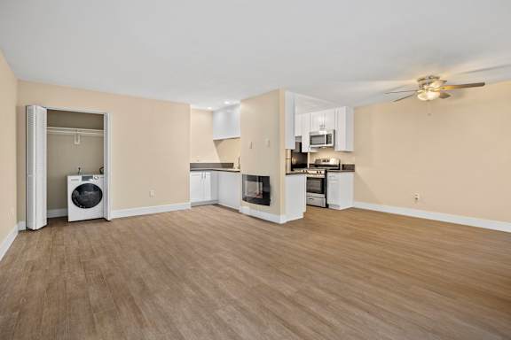 A spacious kitchen and living room with wooden flooring and modern appliances.