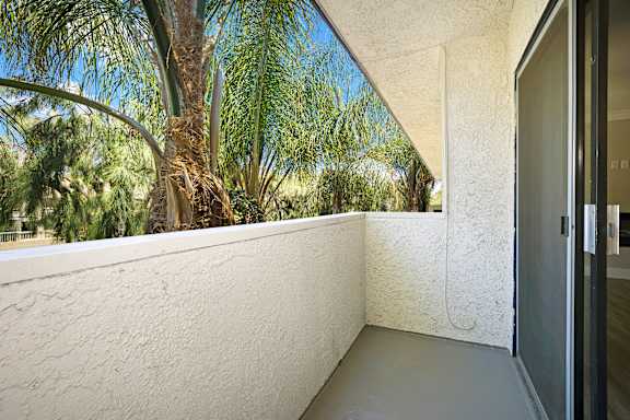 A balcony with a white wall and a door.
